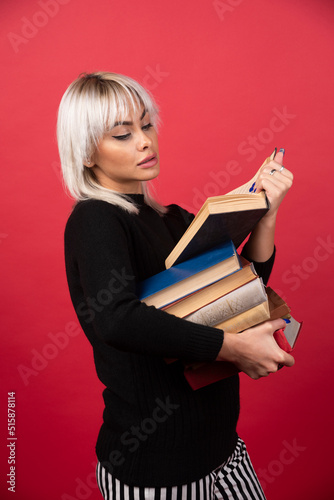 Young woman model reading a book on a red background