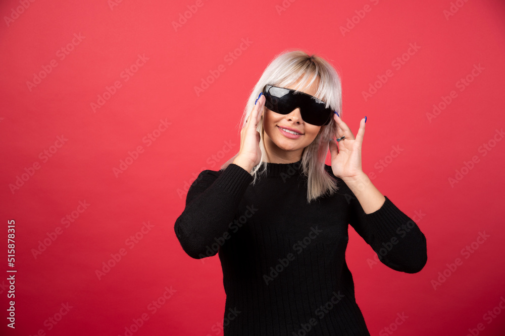Portrait of woman standing and posing with a black glasses on a red background Portrait of woman standing and posing with a black glasses on a red background