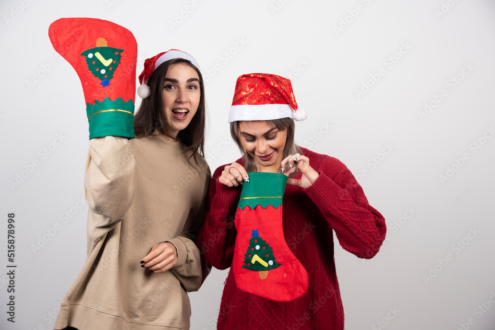 Two smiling girls in Santa hat showing Christmas socks