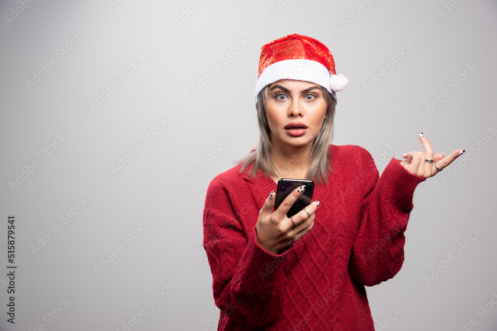 Young woman in red sweater holding cellphone and looking at camera Young woman in red sweater holding cellphone and looking at camera