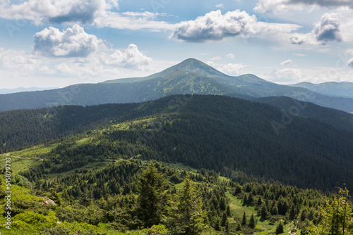The top of Mount Hoverla is covered with green grass and stones on a sunny day, Hiking and tourism in Carpathians