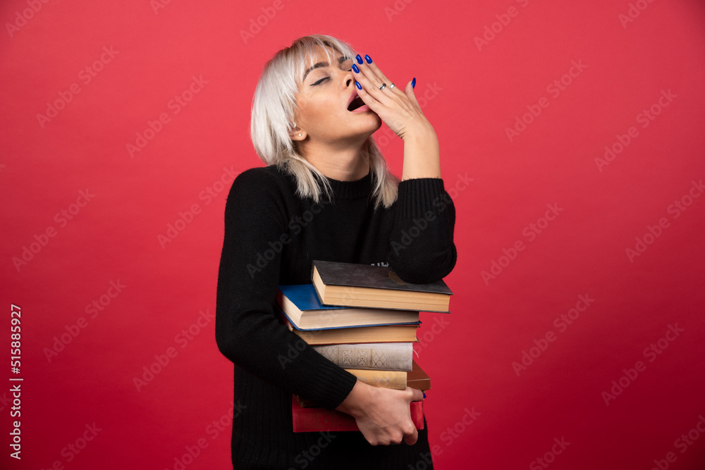 Young woman model holding a lot of books on a red background Young woman model holding a lot of books on a red background
