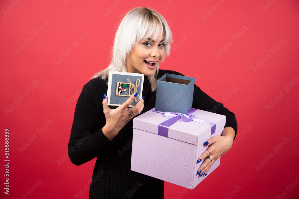 Young woman holding presents on a red background Young woman holding presents on a red background