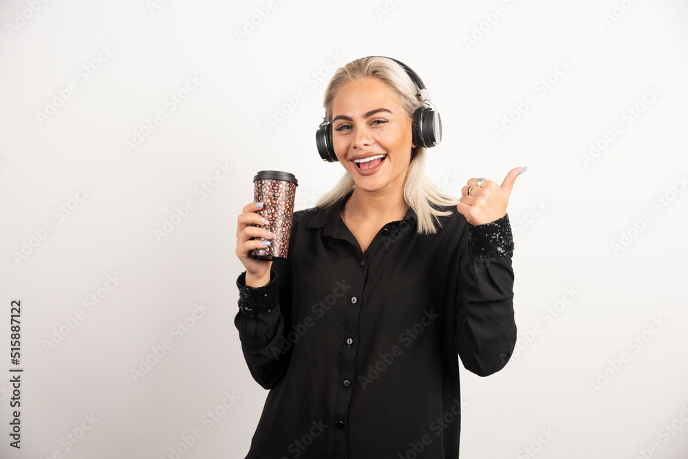 Young woman with cup in headphones on a red background Young woman with cup in headphones on a red background
