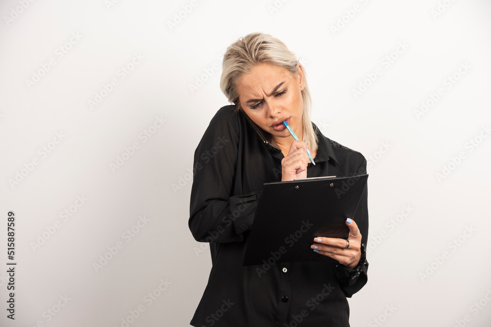 Wondering woman speaking on mobile phone and holding a clipboard
