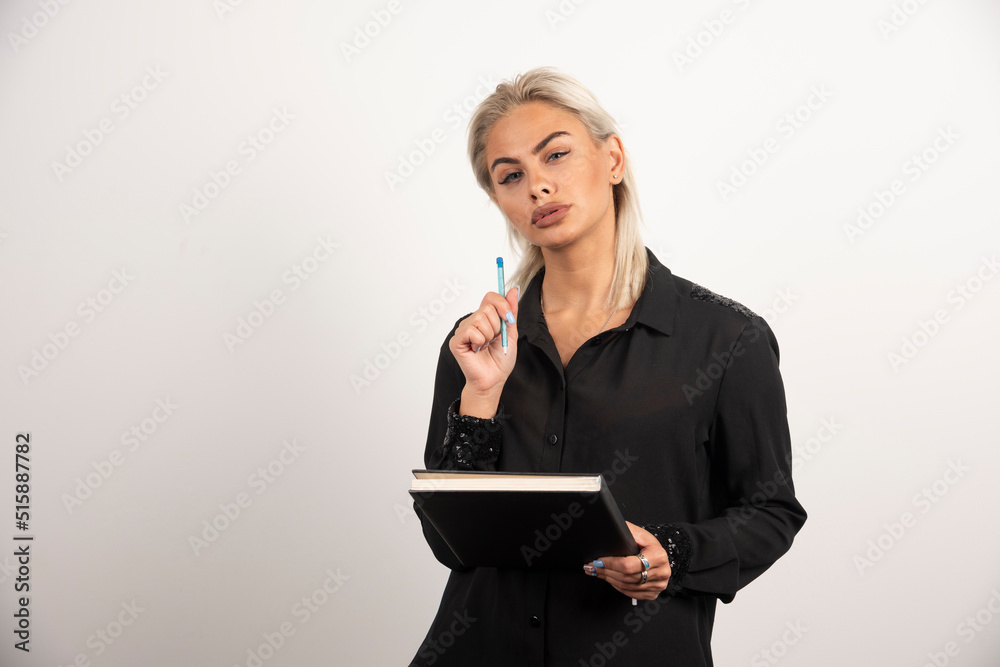 Serious woman posing with a pencil and clipboard on white background