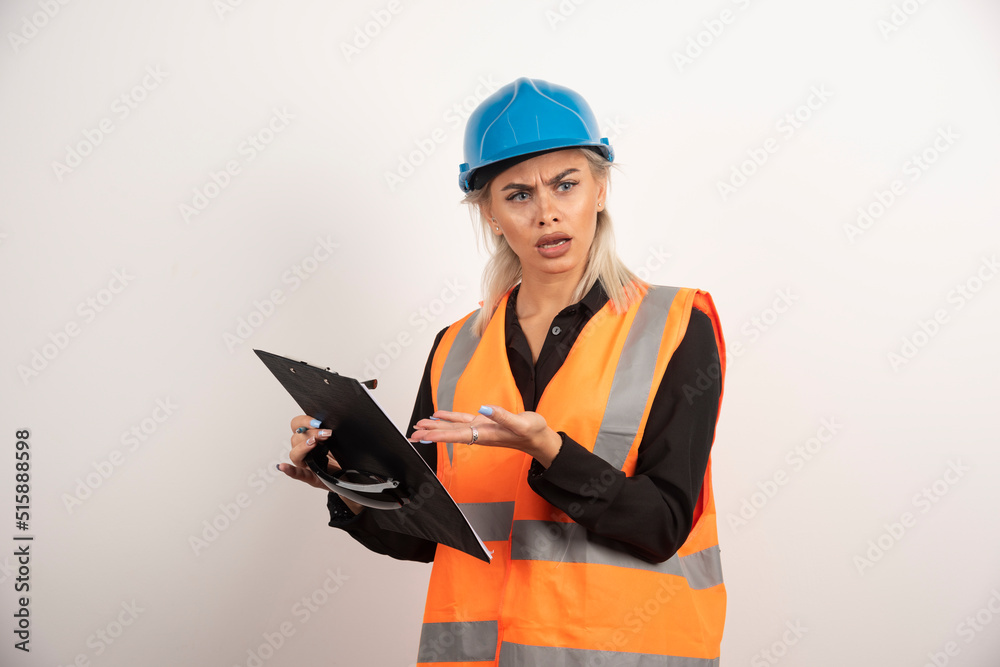 Fototapeta premium Disgruntled woman builder pointing on clipboard