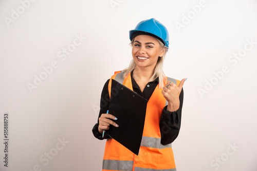 Female worker with clipboard making thumbs up on white background