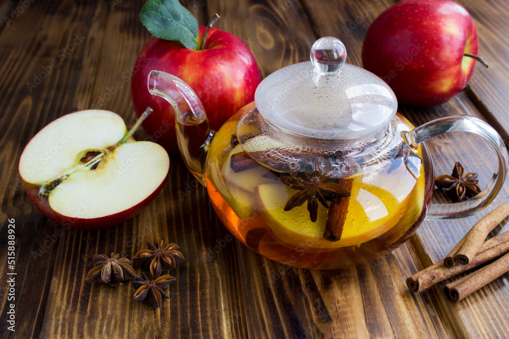 Tea with apple, cinnamon and anise in the glass teapot on the wooden background. Closeup.