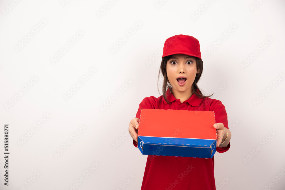 Young smiling woman in red uniform delivering pizza in box