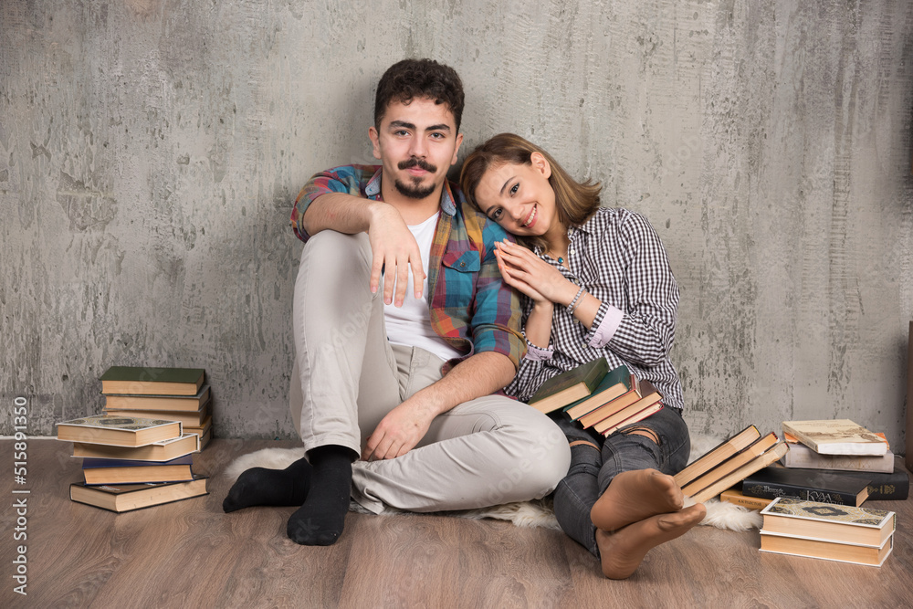 Photo of young smiling couple sitting on the floor with books Photo of young smiling couple sitting on the floor with books