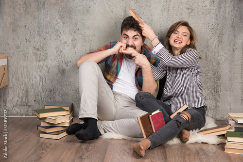 Photo of young couple sitting on the floor with books