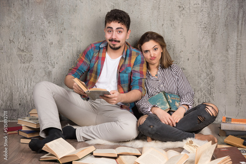 Image of pretty couple sitting on the floor with a lot of books