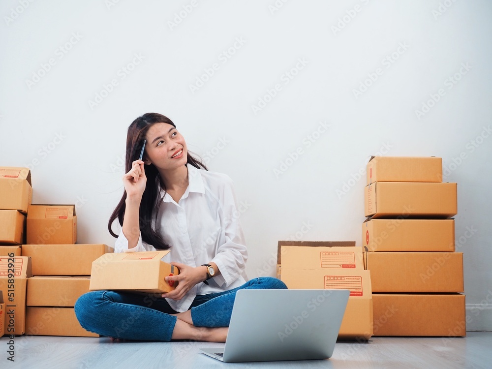 Cheerful Asian people checking order online on laptop,Asian woman packing parcel at home. Cheerful Asian people checking order online on laptop,Asian woman packing parcel at home.