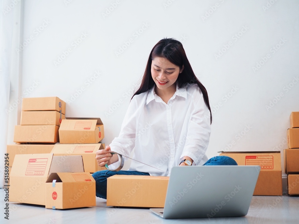 Cheerful Asian people checking order online on laptop,Asian woman packing parcel at home. Cheerful Asian people checking order online on laptop,Asian woman packing parcel at home.