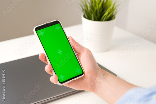 Modern aplications mockup.Smartphone with green chroma screen in hands of unrecognizable man photo