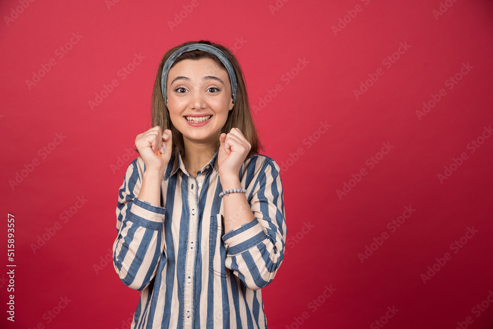 Beautiful girl feeling victorious on red background Beautiful girl feeling victorious on red background