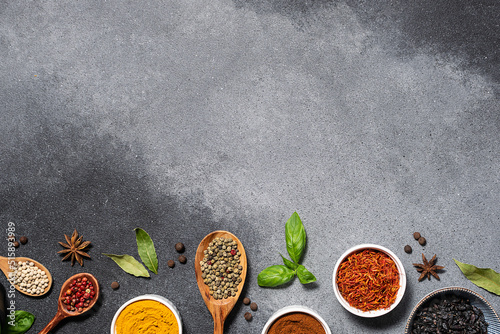 Assortment of aromatic herbs and spices on grey rustic background with copy space for your design top view.
