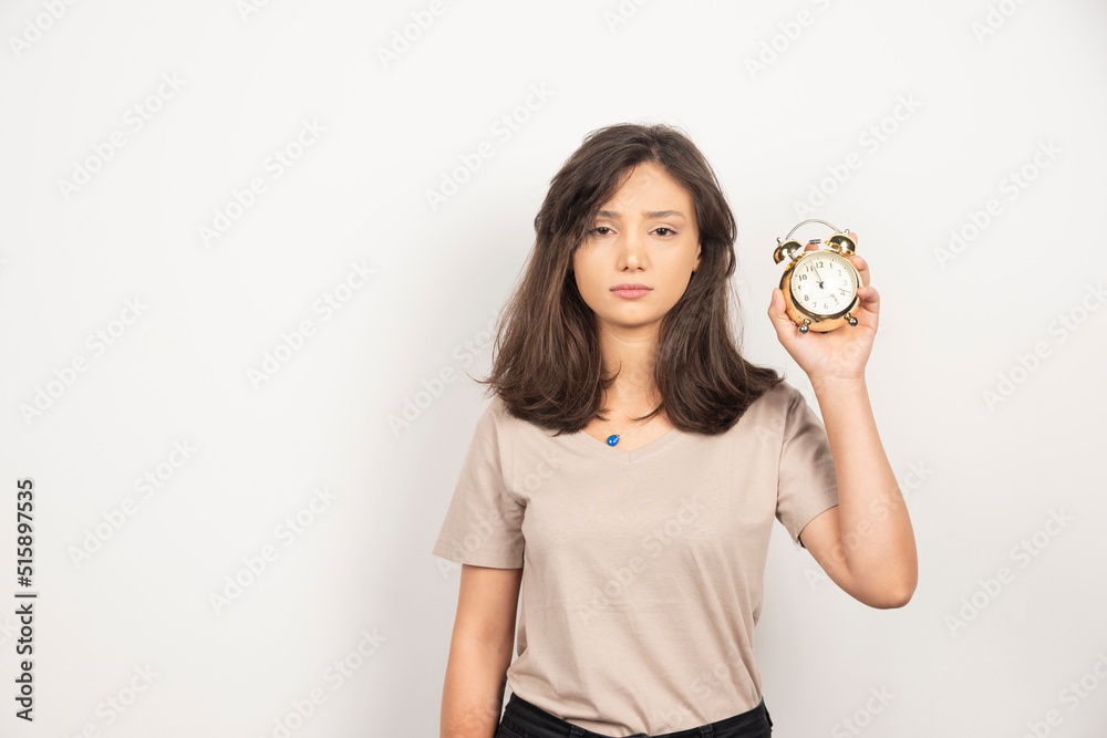 Young woman holding alarm clock on white background Young woman holding alarm clock on white background