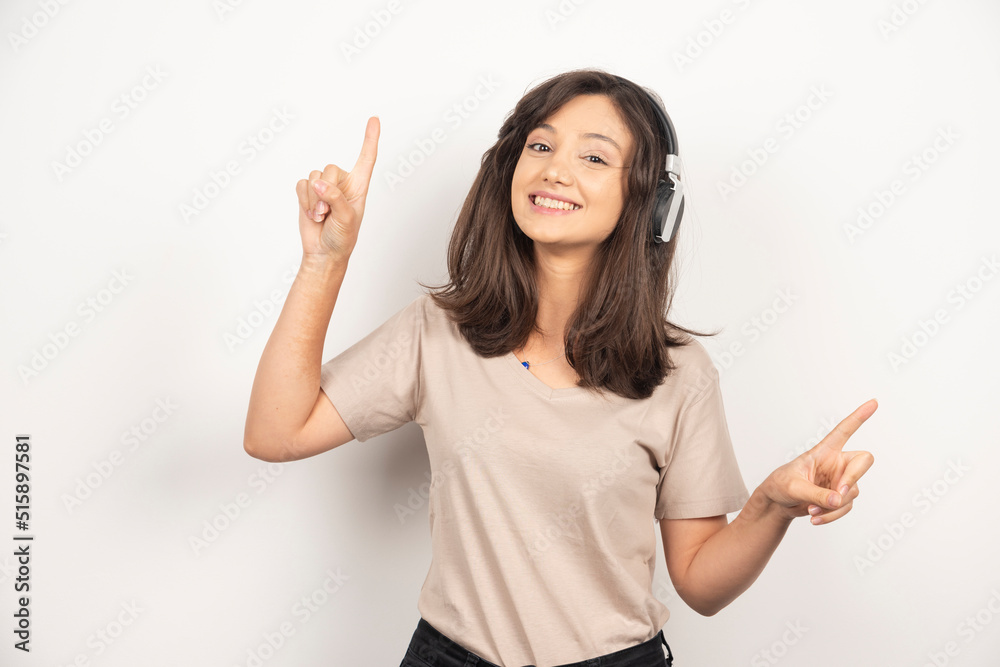 Adorable woman in beige shirt having fun while listening to music using wireless earphones on white background Adorable woman in beige shirt having fun while listening to music using wireless earphones on white background