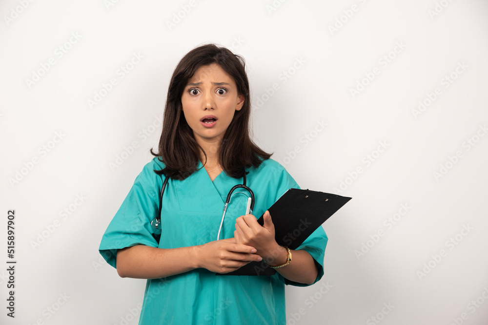 Shocked doctor with stethoscope holding clipboard on white background Shocked doctor with stethoscope holding clipboard on white background