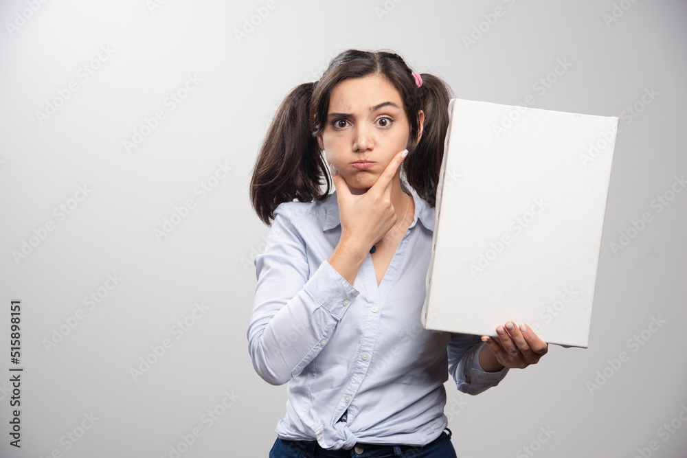 Painter with ponytail holding empty canvas on gray background Painter with ponytail holding empty canvas on gray background