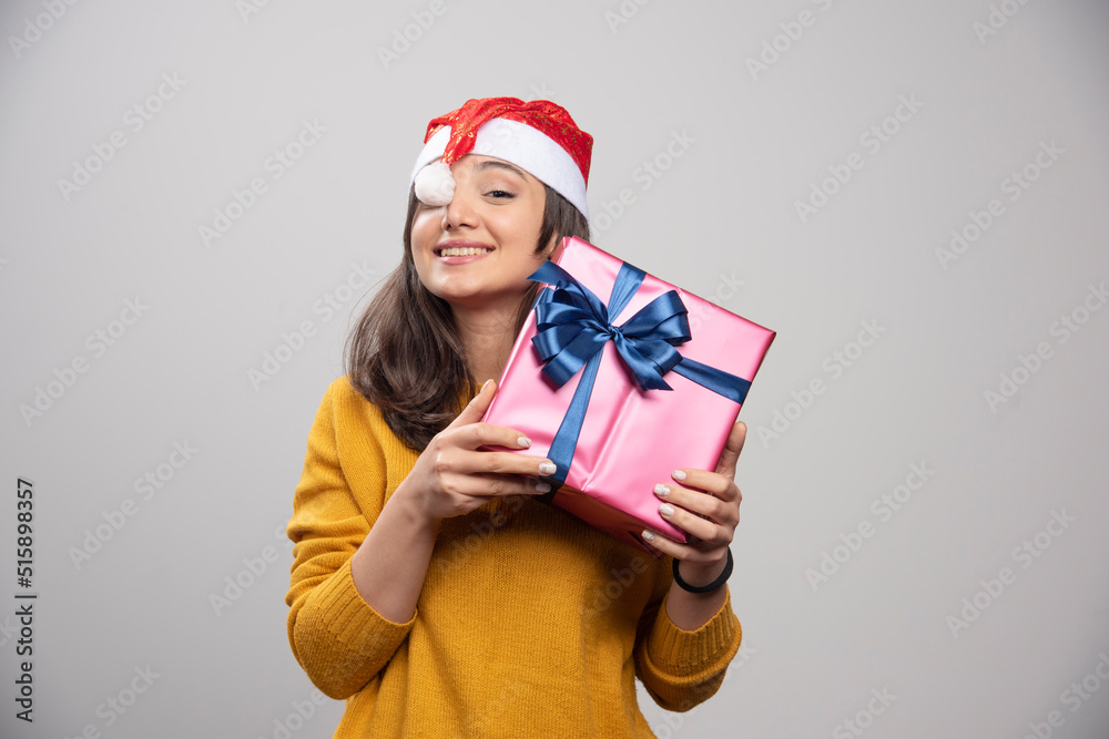 Smiling woman in Santa Claus red hat with Christmas present Smiling woman in Santa Claus red hat with Christmas present