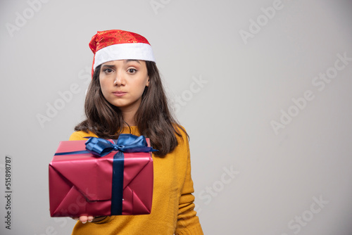 Young woman in Santa hat showing a gift box