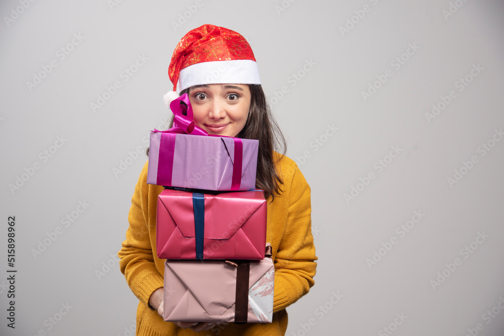 Smiling woman in Santa hat holding gift boxes Smiling woman in Santa hat holding gift boxes