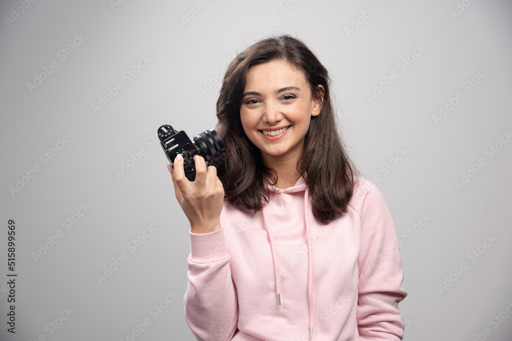 Female photographer smiling with camera on gray background Female photographer smiling with camera on gray background