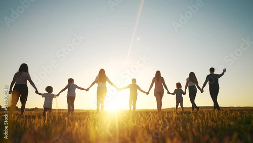 community large family in the park. a large group of people holding hands walking silhouette on nature sunset in the park. big family kid dream concept. people in the park. large family sunlight