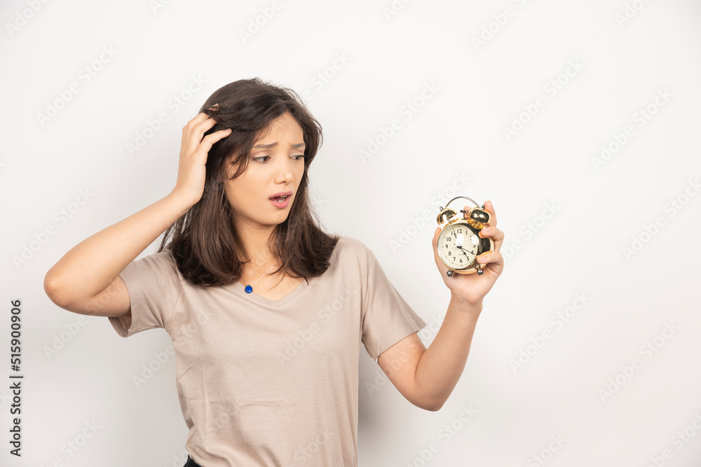 Young woman holding alarm clock on white background Young woman holding alarm clock on white background