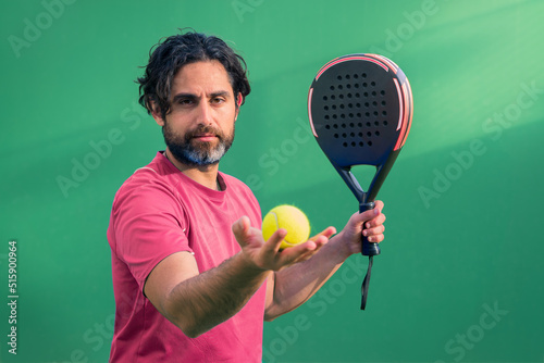 Monitor of padel holding black racket with yellow tennis ball in the hand.
