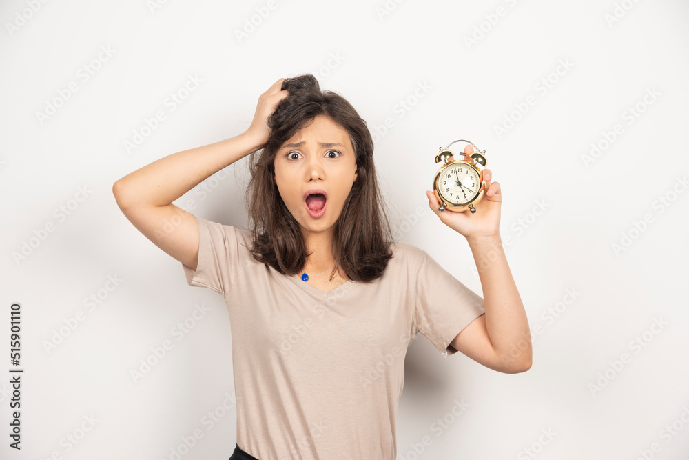 Young woman holding alarm clock on white background Young woman holding alarm clock on white background