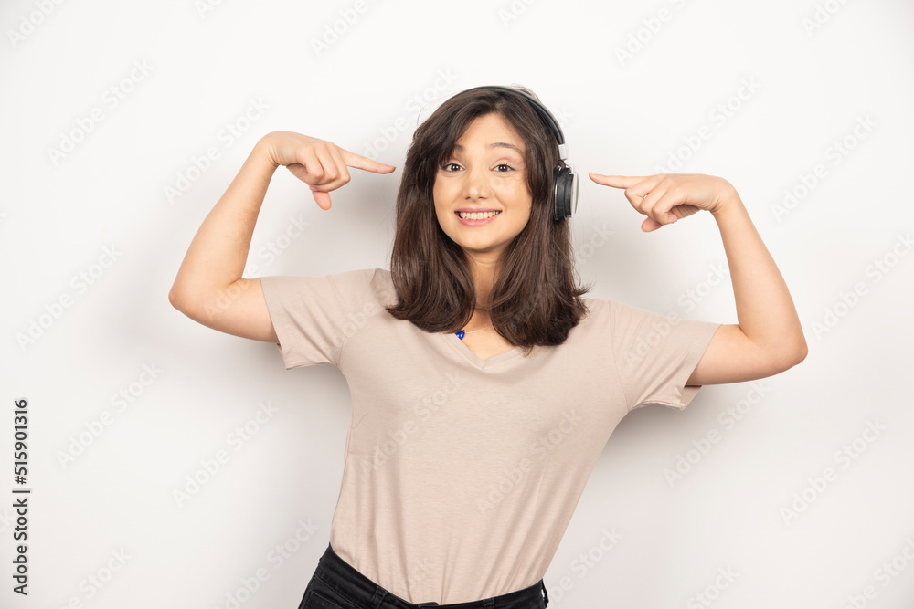 Young woman pointing on headphones on white background Young woman pointing on headphones on white background