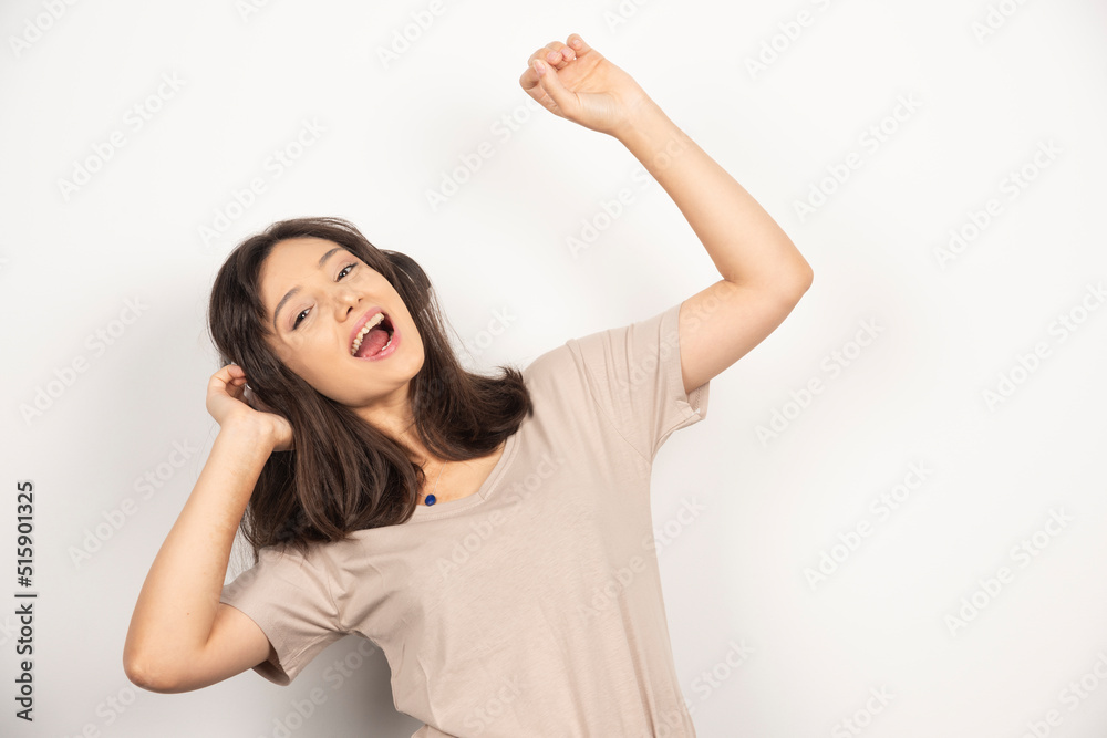 Young woman dancing with hands up on white background
