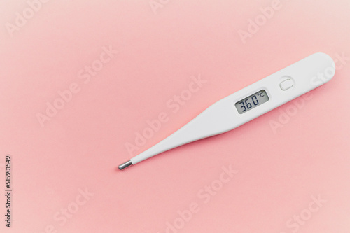 Digital white thermometer with a normal temperature of 36 degrees centigrade on a pink background in the concept of control over health and new emerging viruses for women who are in advanced gestation photo