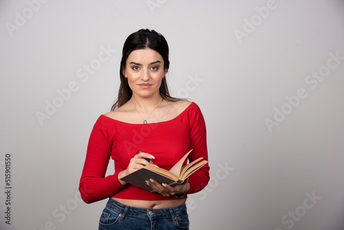 Photo of a cute woman holding an openend book with a pencil photo