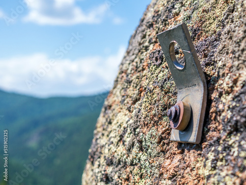 Rock climbing piton (also called a pin or peg) on the stone rock. Close-up, selective focus © vadim