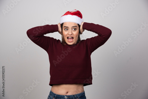 Photo of screaming woman in Christmas hat covering ears