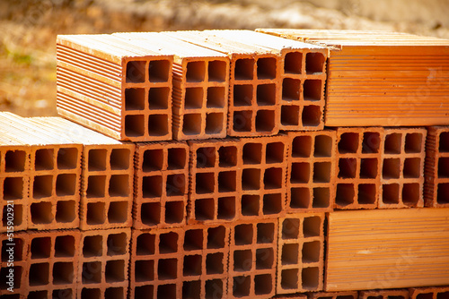 Detalhe de tijolos empilhados.
Tijolos cerâmicos dispostos em pilhas e armazenados ao ar livre para venda. photo