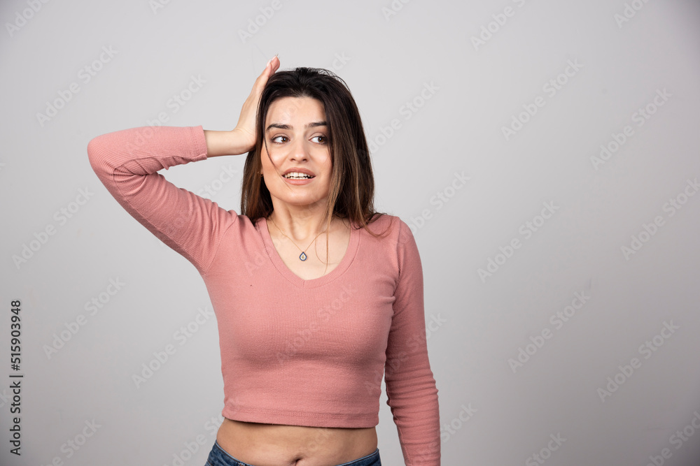 A young attractive woman dressed in casual clothes holding raised palm on her head A young attractive woman dressed in casual clothes holding raised palm on her head