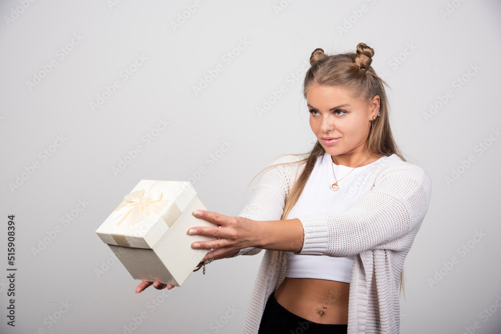 Blonde woman in winter outfit offering gift box Blonde woman in winter outfit offering gift box