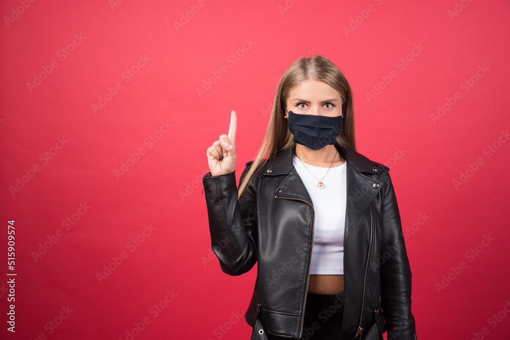 Beautiful young woman with a medical face mask pointing up