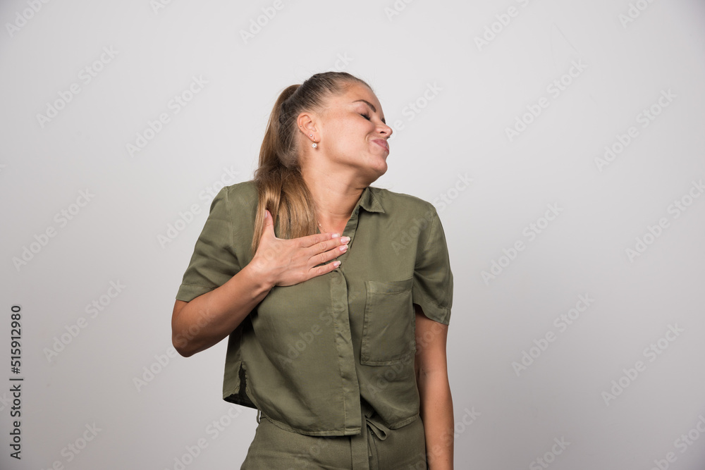 Young woman holding her heart on gray background Young woman holding her heart on gray background