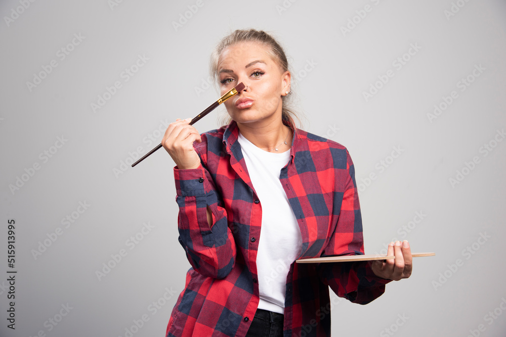 Blonde artist putting a painting brush to her nose and thinking Blonde artist putting a painting brush to her nose and thinking
