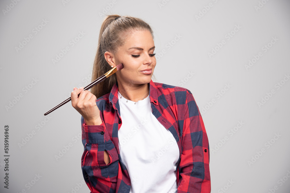 Blonde artist in checked shirt feels glamour and confident with paint brushes in the hand Blonde artist in checked shirt feels glamour and confident with paint brushes in the hand