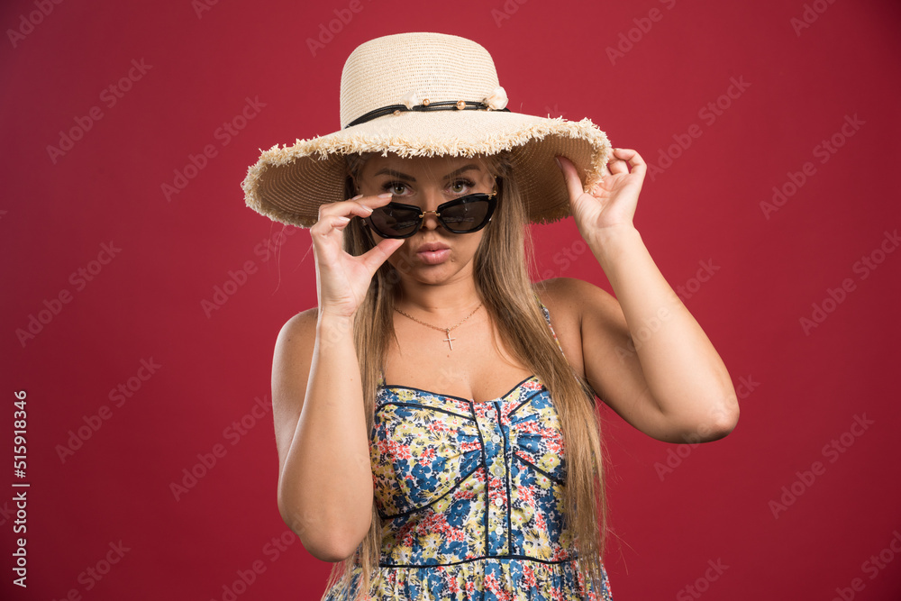 Blonde woman posing with hat and glasses on red background Blonde woman posing with hat and glasses on red background