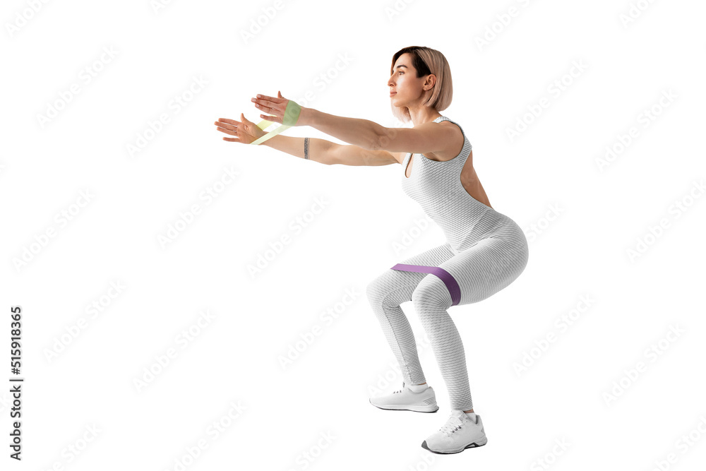 Obraz premium Sexy woman in sportswear using a resistance band in her exercise routine. Young woman performs fitness exercises on white background. Isolate