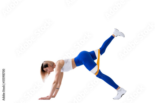 Sexy woman in sportswear using a resistance band in her exercise routine. Young woman performs fitness exercises on white background. Isolate